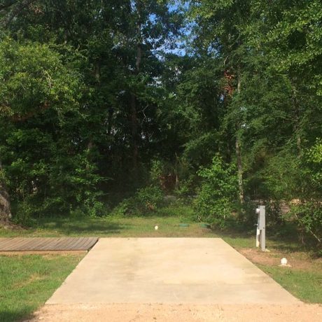 concrete RV pad surrounded by grass and trees